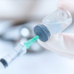 Doctor's hand sucking injection medicine from vial bottle